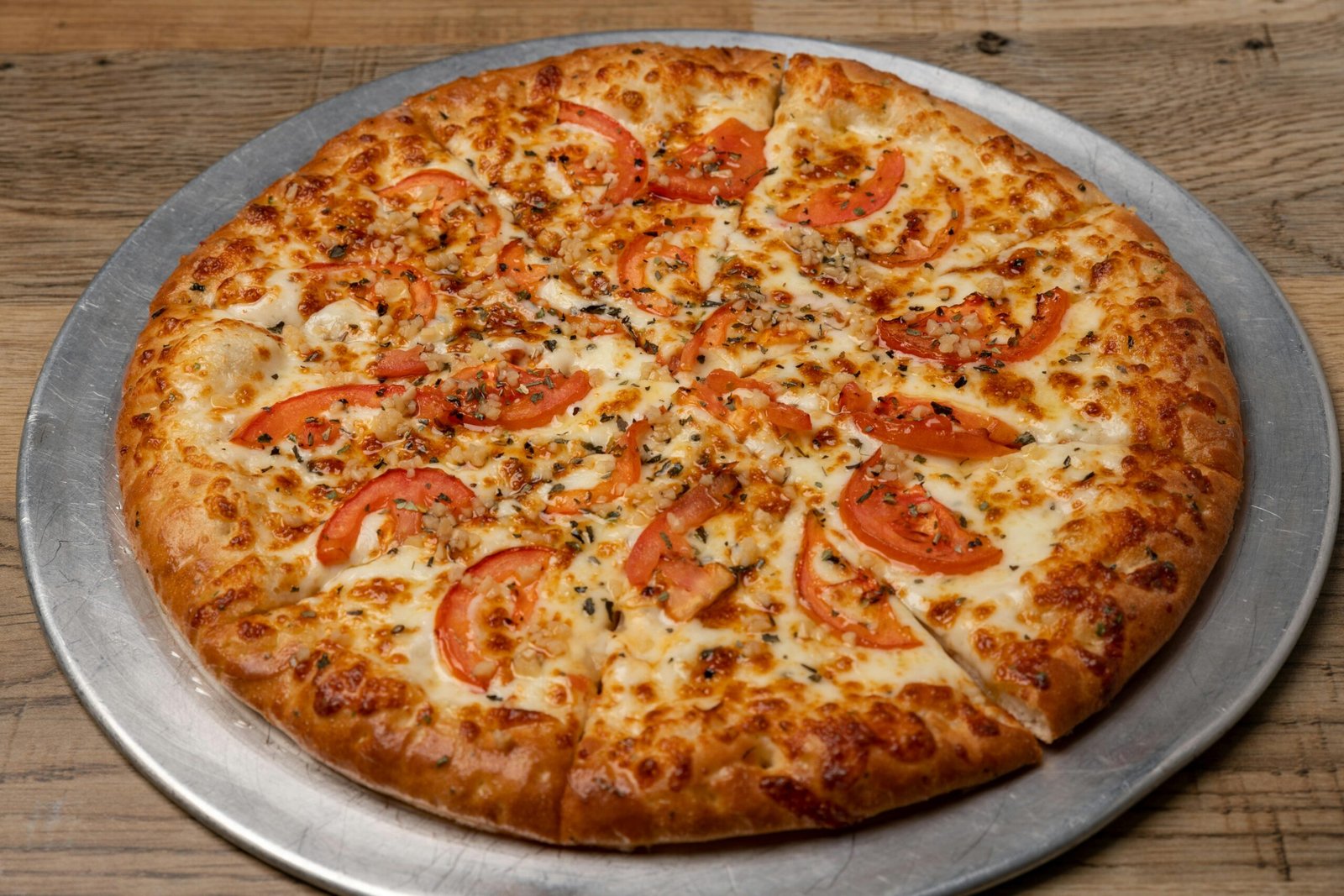 Savor a freshly baked Margherita pizza topped with ripe tomatoes and melted mozzarella cheese.