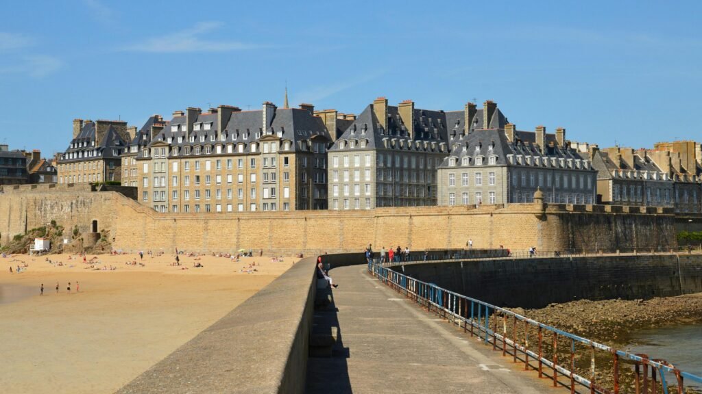 Historic Saint-Malo beach and walls under blue skies, perfect for travel and architecture.