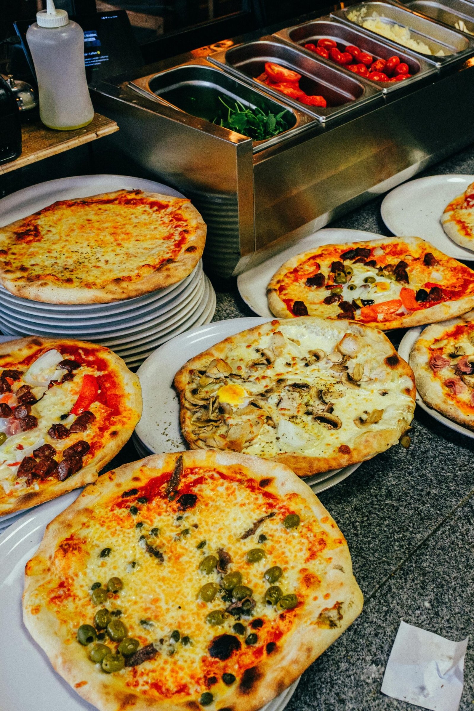 Multiple freshly baked pizzas displayed in a restaurant setting, showcasing assorted toppings.