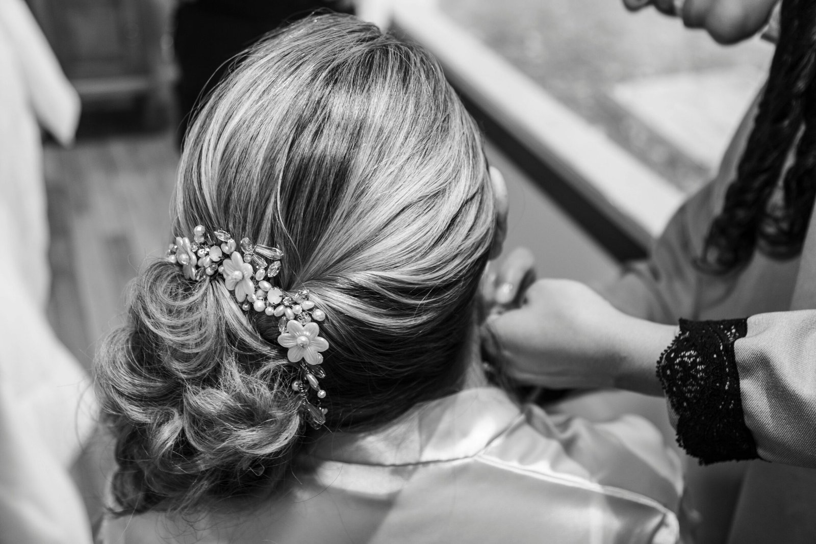Back view of elegant bridal hairstyle with floral accessories during preparation.
