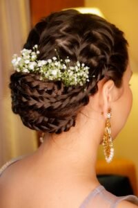 Close-up of a woman's braided bridal hairstyle adorned with delicate flowers and gold earrings.