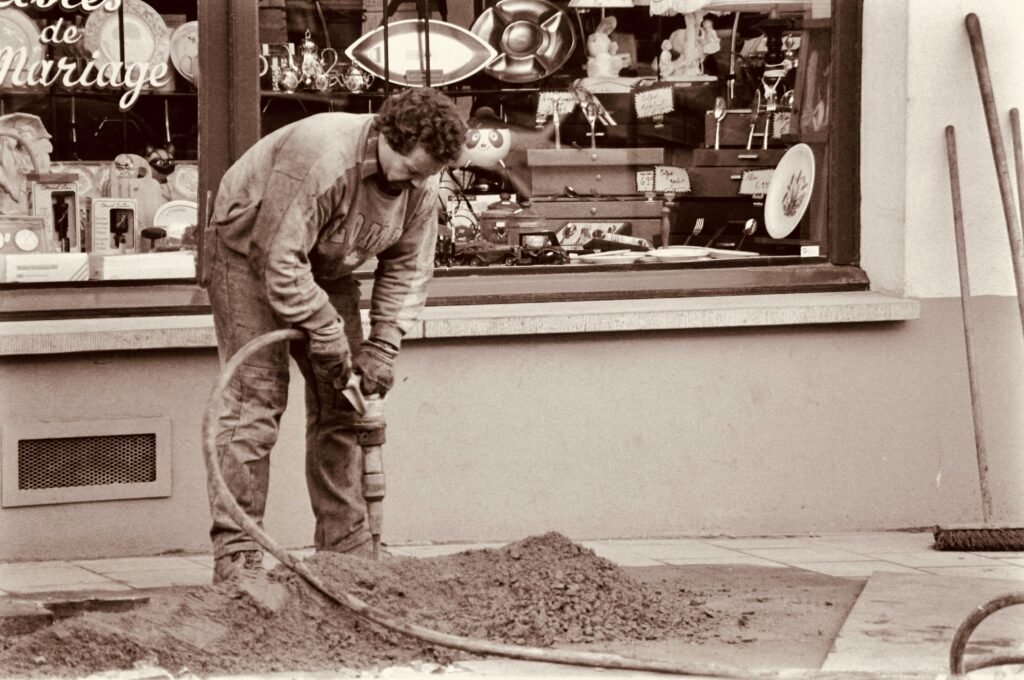 Sepia-toned image of a construction worker using equipment on a city street.